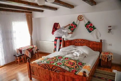 Cameră cu pat din lemn și cearșaf cu motive tradiționale